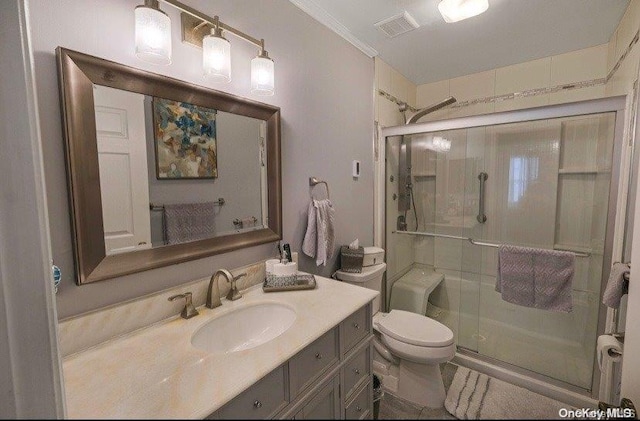 bathroom featuring vanity, toilet, a shower with door, and crown molding