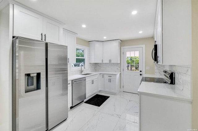 kitchen featuring white cabinets, appliances with stainless steel finishes, light stone counters, and sink