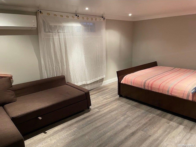 bedroom with wood-type flooring, a wall unit AC, and ornamental molding