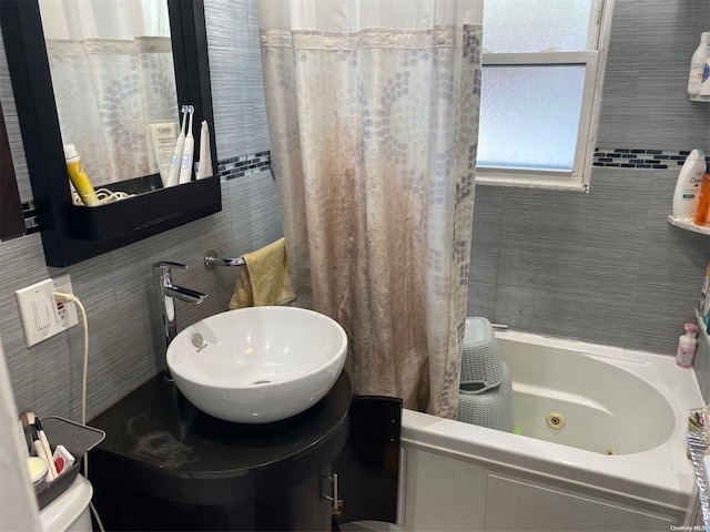 bathroom featuring shower / bath combination with curtain, tile walls, and sink