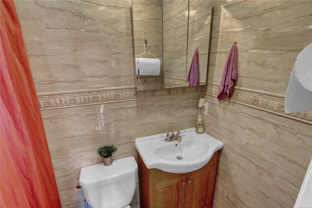 bathroom featuring vanity, toilet, and tile walls