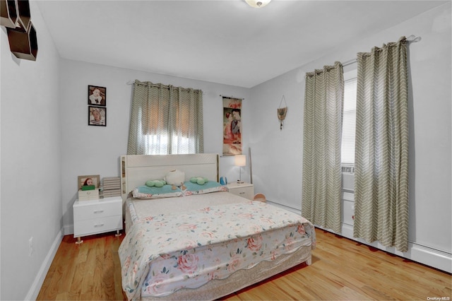 bedroom with multiple windows and light hardwood / wood-style flooring