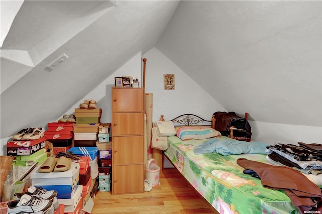 bedroom with light hardwood / wood-style floors and lofted ceiling