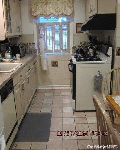 111 President St, Hempstead, NY 11550 - kitchen featuring exhaust hood, white range with gas cooktop, light tile patterned floors, dishwasher, and light countertops