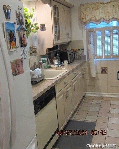 111 President St, Hempstead, NY 11550 - kitchen with white appliances, light countertops, light tile patterned flooring, and glass insert cabinets