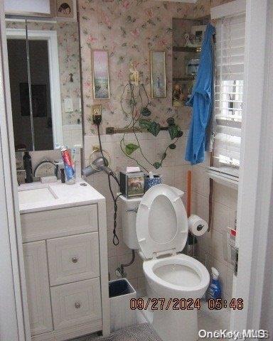 bathroom with vanity, toilet, and tile walls