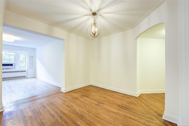 empty room featuring hardwood / wood-style floors and a notable chandelier