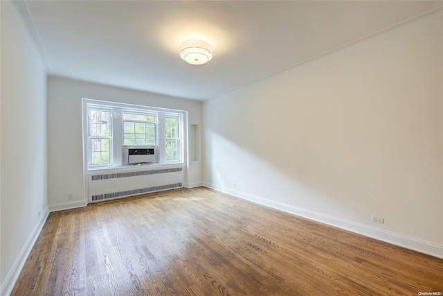 spare room featuring radiator and hardwood / wood-style flooring