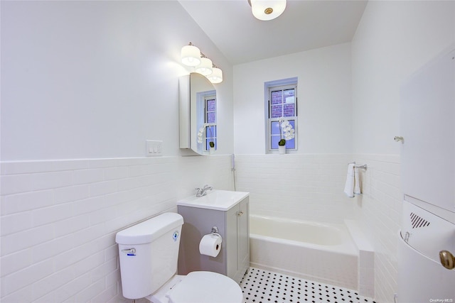 bathroom with a bathing tub, vanity, tile walls, and toilet