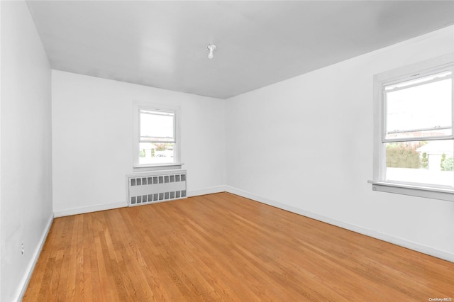 unfurnished room featuring radiator heating unit and light wood-type flooring