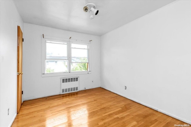 empty room featuring radiator and light hardwood / wood-style flooring