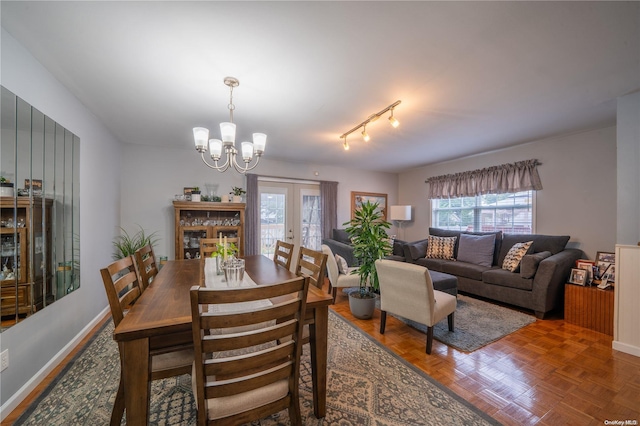 dining area featuring rail lighting, parquet floors, french doors, and an inviting chandelier