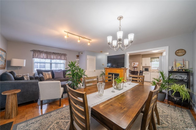 dining room with parquet flooring, rail lighting, and a notable chandelier