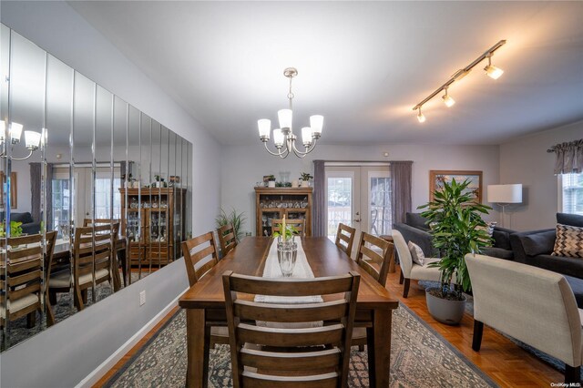 dining space with a chandelier, parquet flooring, rail lighting, and french doors