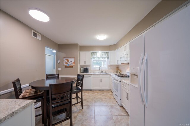 kitchen featuring white cabinetry, sink, white appliances, decorative backsplash, and light tile patterned floors