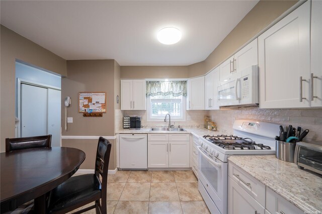 kitchen with white appliances, sink, decorative backsplash, light stone countertops, and white cabinetry