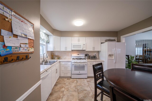 kitchen featuring white appliances, tasteful backsplash, white cabinetry, and sink