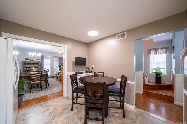 dining space featuring a notable chandelier, light parquet floors, a wealth of natural light, and french doors