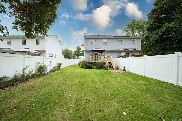 back of property with a wooden deck and a yard