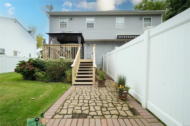 rear view of property featuring a yard, a patio, and a deck