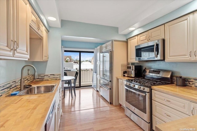 kitchen with wood counters, appliances with stainless steel finishes, light wood-type flooring, and sink