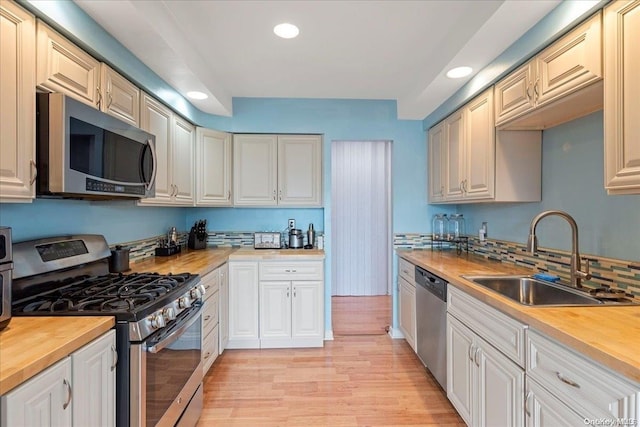 kitchen with light hardwood / wood-style flooring, stainless steel appliances, butcher block countertops, and sink