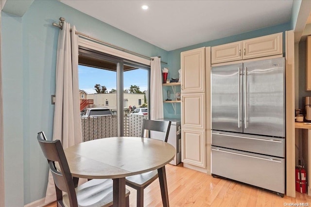 kitchen with cream cabinetry, high end refrigerator, and light wood-type flooring