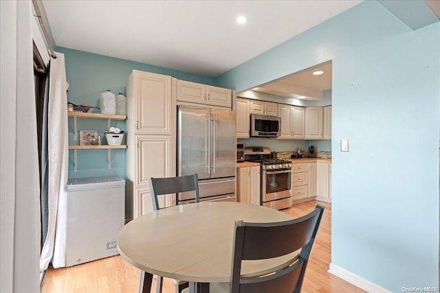 kitchen with light wood-type flooring, stainless steel appliances, and cream cabinets