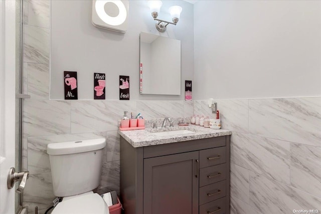 bathroom featuring vanity, toilet, and tile walls