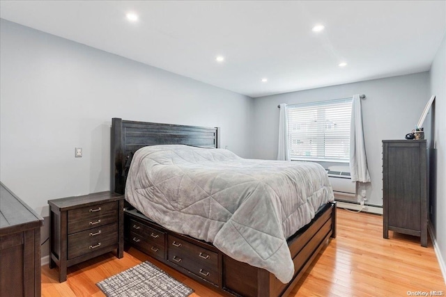 bedroom with light hardwood / wood-style floors and a baseboard radiator