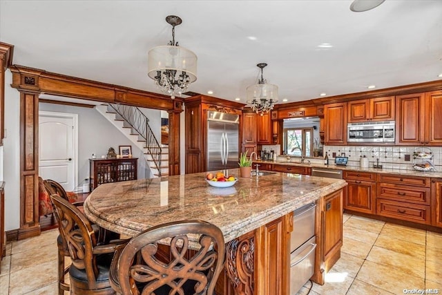 kitchen featuring light stone countertops, tasteful backsplash, built in appliances, decorative light fixtures, and a notable chandelier