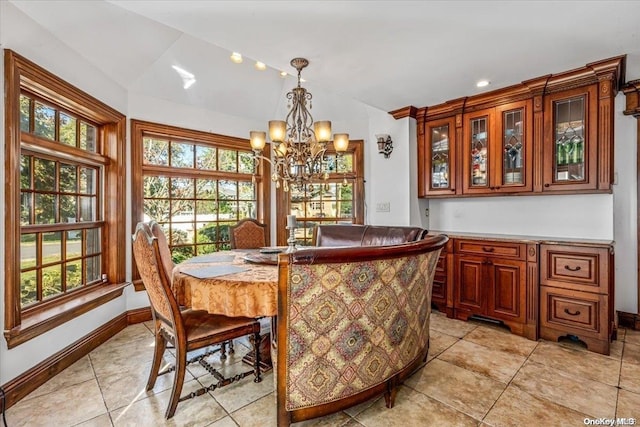 tiled dining area featuring a healthy amount of sunlight, lofted ceiling, and an inviting chandelier