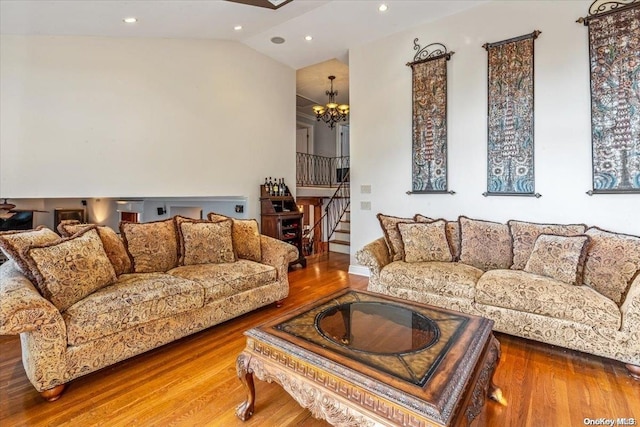 living room with hardwood / wood-style floors, a notable chandelier, and lofted ceiling