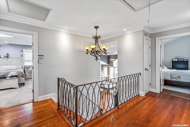 corridor featuring hardwood / wood-style floors, ornamental molding, and an inviting chandelier