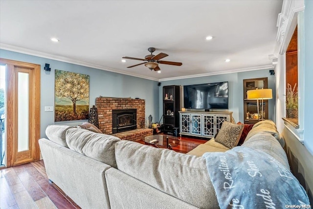 living room featuring a wood stove, ceiling fan, hardwood / wood-style floors, and ornamental molding