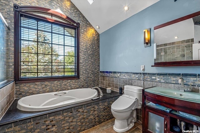 bathroom with tile patterned flooring, lofted ceiling, toilet, vanity, and tile walls