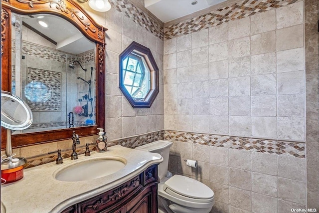 bathroom featuring a tile shower, vanity, tile walls, and toilet