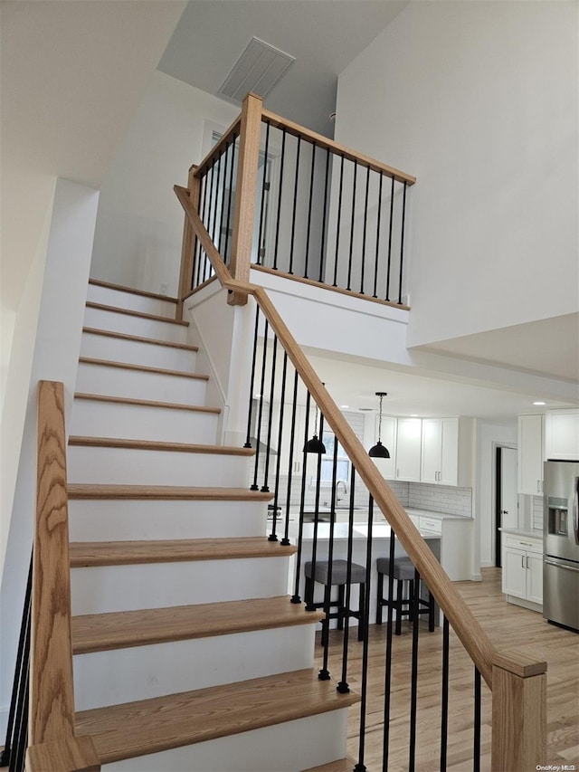 stairs with hardwood / wood-style flooring and a high ceiling