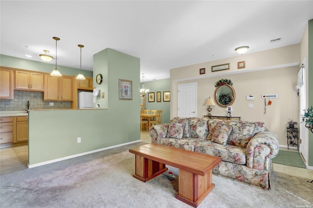 living room with light carpet, a chandelier, and sink