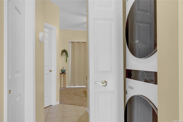 laundry area with light tile patterned flooring and stacked washer / drying machine