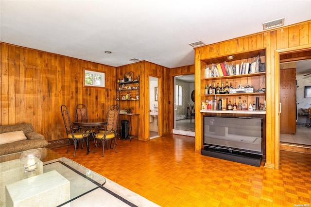 living room with parquet floors, wooden walls, and a baseboard heating unit