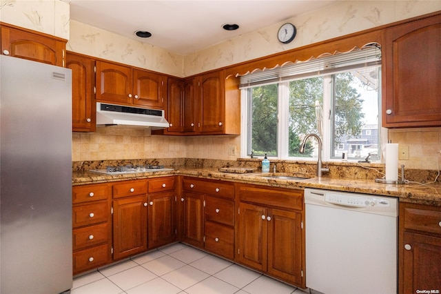 kitchen featuring light stone countertops, white appliances, sink, and light tile patterned floors