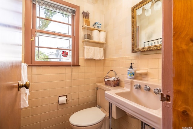 bathroom featuring toilet, tile walls, and sink