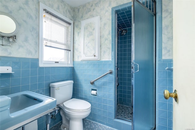 bathroom with walk in shower, toilet, tile walls, and sink