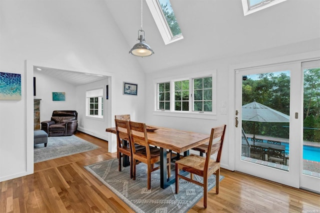 19 Oceanview Rd, Hampton Bays, NY 11946 - dining space featuring a skylight, light wood finished floors, baseboard heating, and high vaulted ceiling