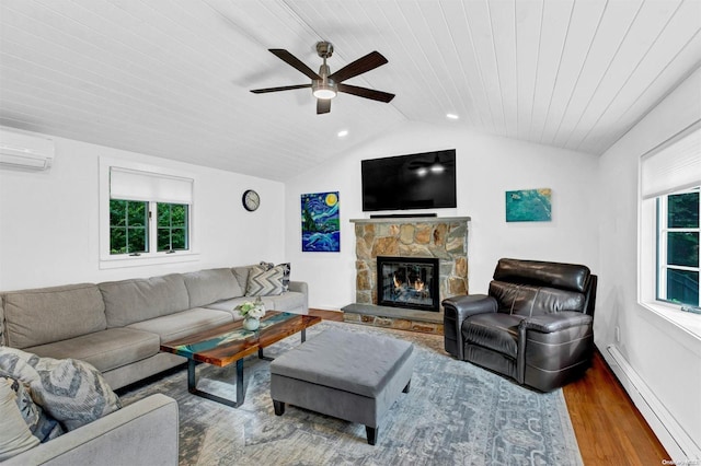 living room featuring a baseboard radiator, a stone fireplace, a wall unit AC, lofted ceiling, and hardwood / wood-style flooring