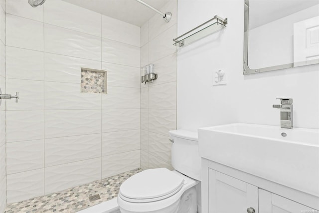 bathroom with tiled shower, vanity, and toilet