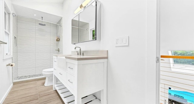 bathroom with tiled shower, vanity, and toilet