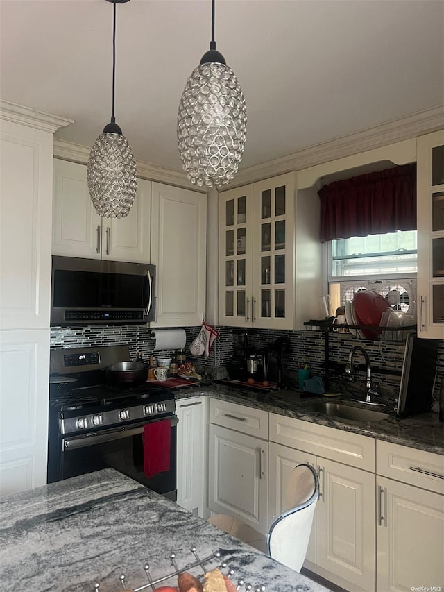 kitchen featuring tasteful backsplash, stainless steel appliances, sink, pendant lighting, and dark stone countertops