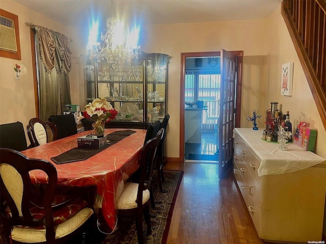 dining room with dark hardwood / wood-style flooring, a wall mounted AC, and a chandelier